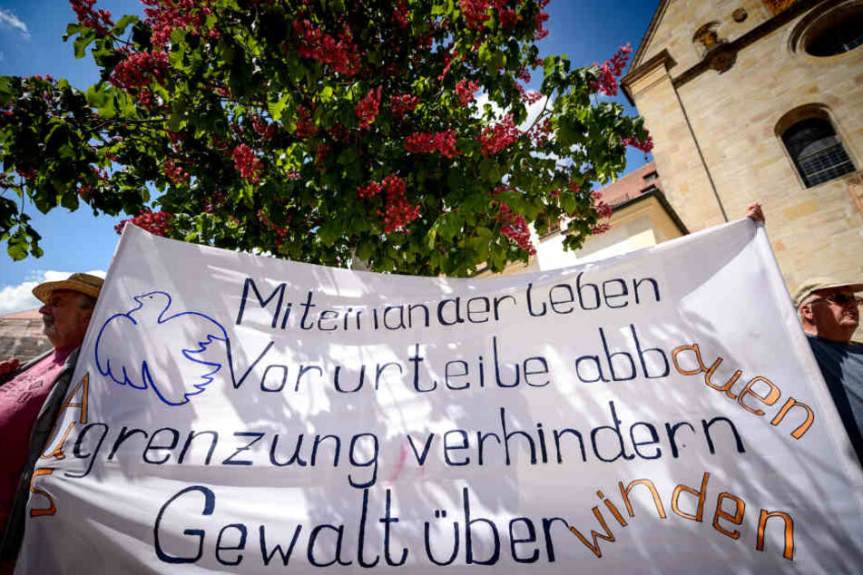 Teilnehmer einer Mahnwache halten ein Plakat hoch. Die Gruppe "Mahnwache Ellwangen" kritisiert den Polizeieinsatz in der Flüchtlingsunterkunft Ellwangen.