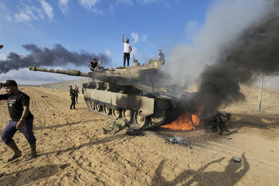 Palästinenser feiern an einem zerstörten israelischen Panzer am Zaun des Gazastreifens östlich von Khan Younis die blutigen Angriffe.