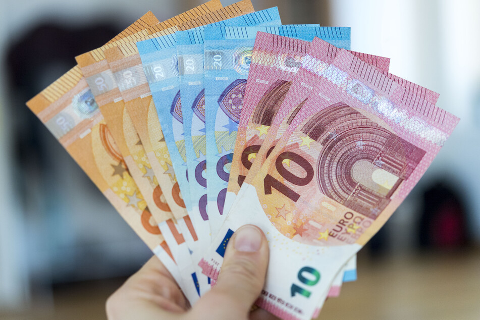 Eine Frau hält Banknoten von 10, 20 und 50 Euro gefächert in der Hand. (Symbolbild)