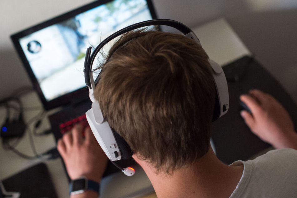 Ein Junge sitzt mit einem Headset vor einem Laptop und spielt ein Online-Computerspiel. (Symbolbild)