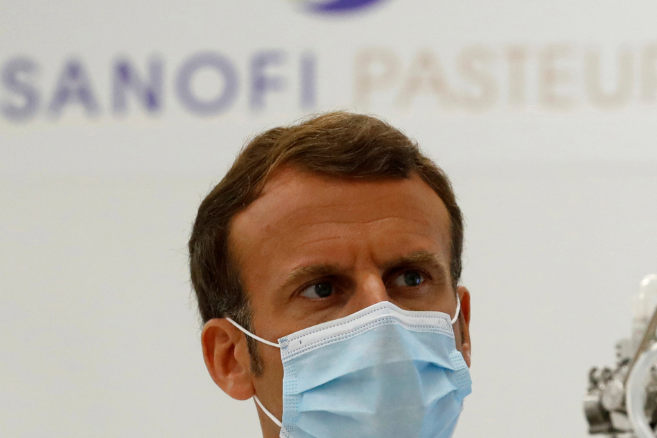 Frankreich, Marcy-L'etoile: Emmanuel Macron, Präsident von Frankreich, trägt bei einem Besuch einer Fabrik des Pharmaherstellers Sanofi Pasteur einen medizinischen Mundschutz.