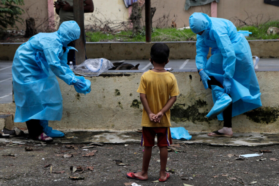 Indien, Mumbai: Mitarbeiter des Gesundheitswesens ziehen ihre Schutzbekleidung aus, nachdem sie die Anwohner eines Slums auf Covid-19-Symptome untersucht hatten.