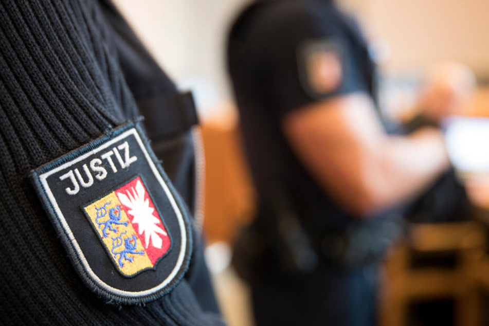 Justizbeamte stehen im Gerichtssaal. (Archivbild)