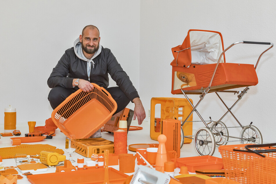Künstler Martin Maleschka und ein Teil der (überwiegend orangefarbenen) Ausstellungsstücke von „Wohnmaschine 2.0“.