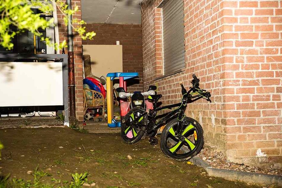 Unter dem Fenster stehen das Fahrrad des toten Jungen und anderes Spielzeug.
