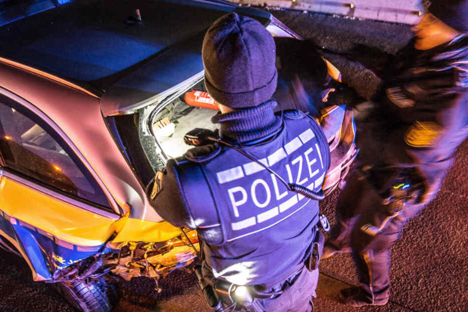 Zwei Beamte stehen vor dem demolierten Streifenwagen.