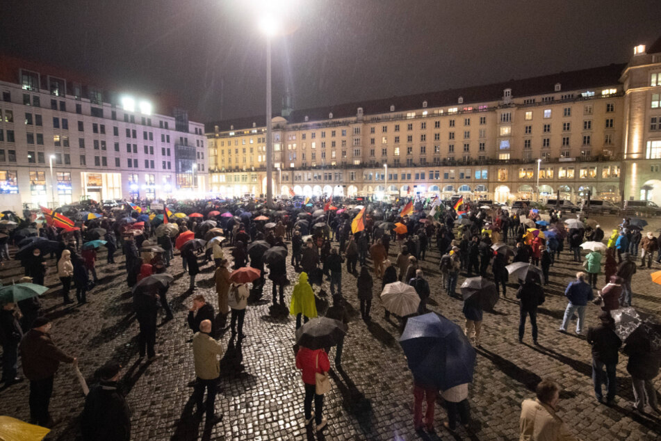 Teilnehmer der Pegida-Demonstration stehen mit Corona-Abstand auf dem Altmarkt.