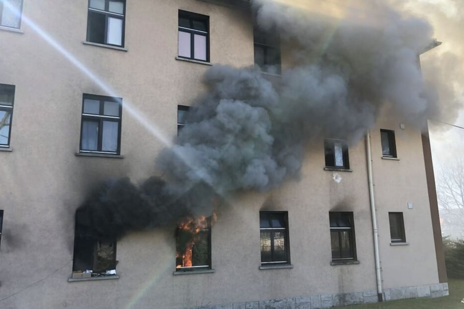 Schwarzer Rauch steigt aus einem Fenster der Unterkunft empor.