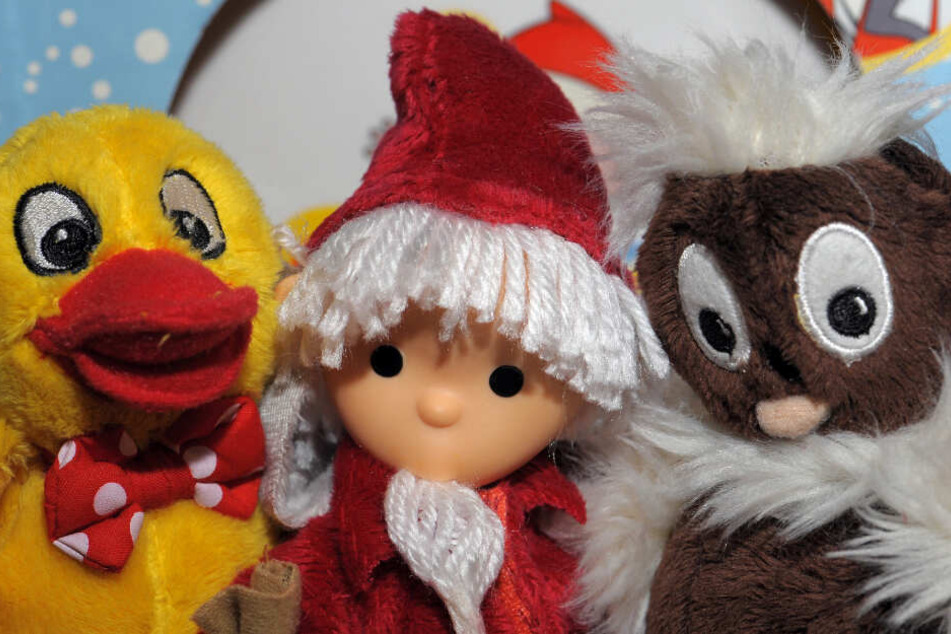 Das Sandmännchen sitzt nach einer Pressekonferenz in Berlin in einem Regal des rbb-Shops mit seinen Freunden Pittiplatsch (r) und Schnatterinchen.
