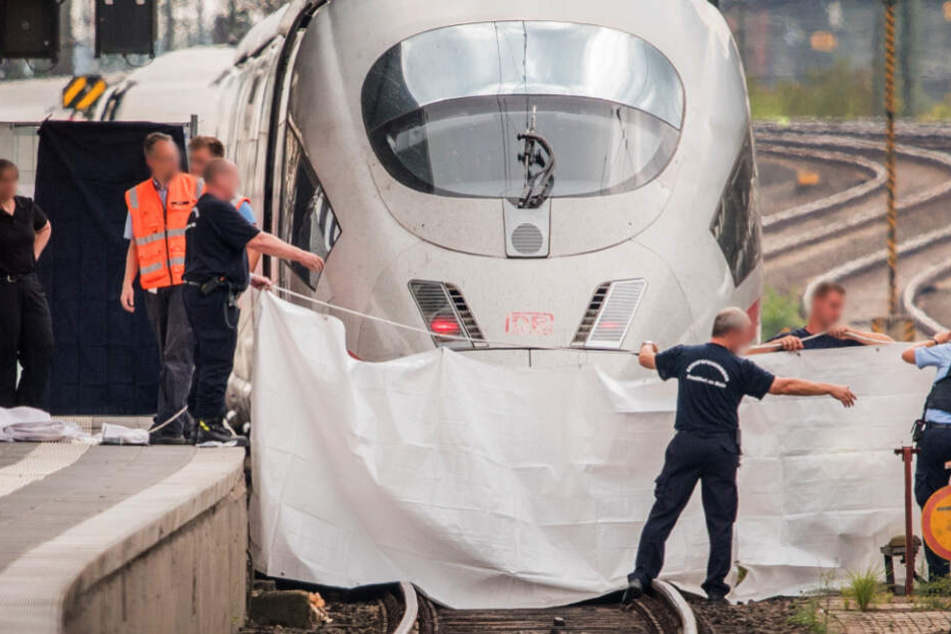 Polizisten und Feuerwehrleute spannen am 29.07.2019 im Frankfurter Hauptbahnhof eine weiße Plane als Sichtschutz vor einen ICE.