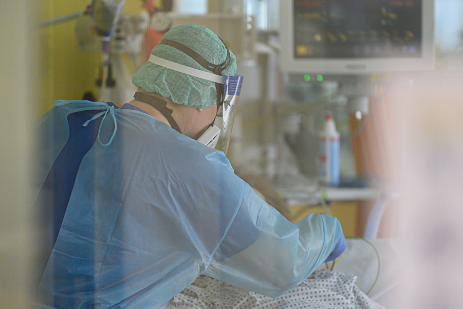 Ein Intensivpfleger ist auf der Covid-19-Intensivstation im Städtischen Klinikum Dresden mit der Versorgung von Corona-Patienten beschäftigt.