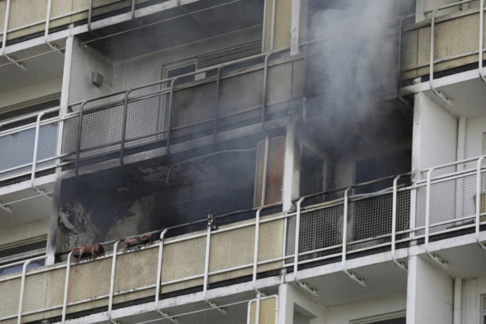 Der Balkon ist völlig verkohlt, aus der Brandwohnung quillt noch Rauch.