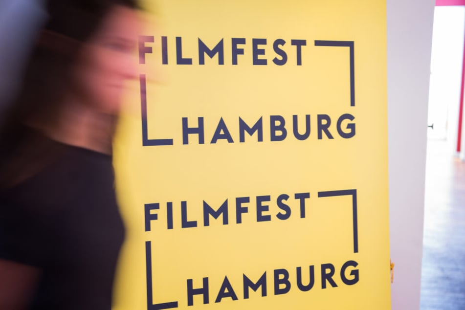 Eine Frau läuft an einem Aufsteller des Filmfests Hamburg vorbei.