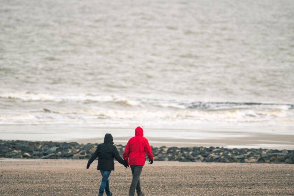 Passanten gehen am Strand von Norderney spazieren.