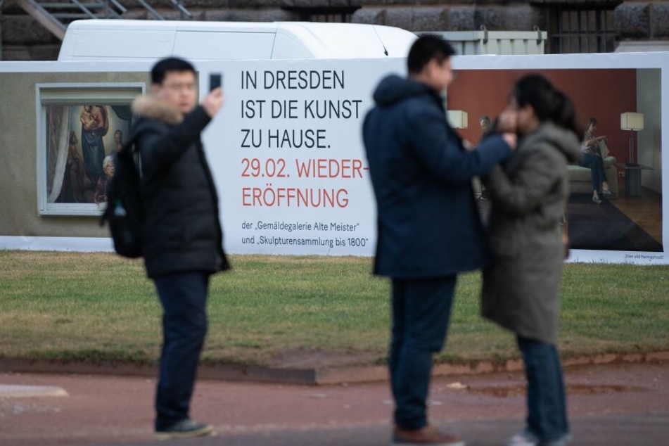 Touristen stehen im Zwinger vor einem Bauzaun des Semperbaus mit der Gemäldegalerie Alte Meister.