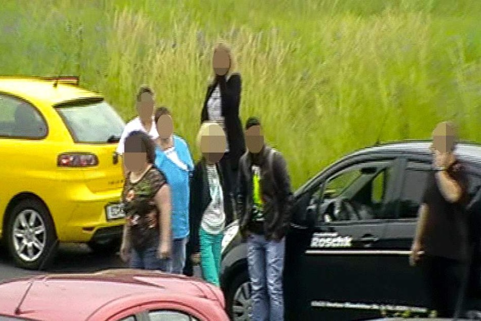 Der "Verletzte" steht neben dem Auto, während der Fahrer (re.) telefoniert, um Hilfe zu rufen.