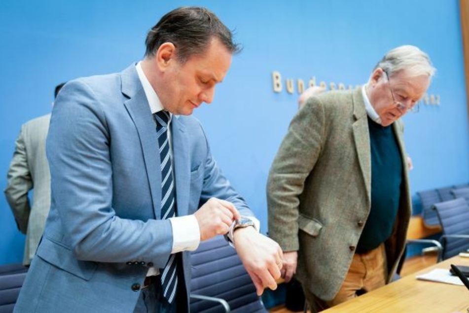 Tino Chrupalla (l.), AfD-Bundessprecher, blickt neben Alexander Gauland, Fraktionsvorsitzender der AfD, in der Bundespressekonferenz auf seine Uhr.