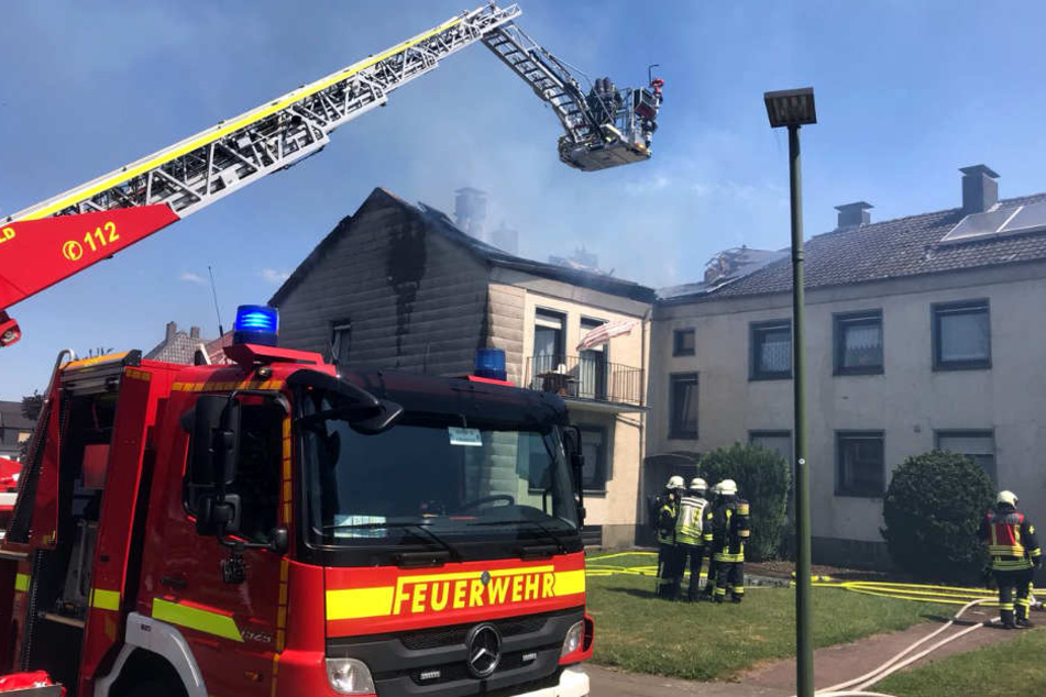 Mit einer Drehleiter kämpft die Feuerwehr gegen die Flammen im Dachstuhl.