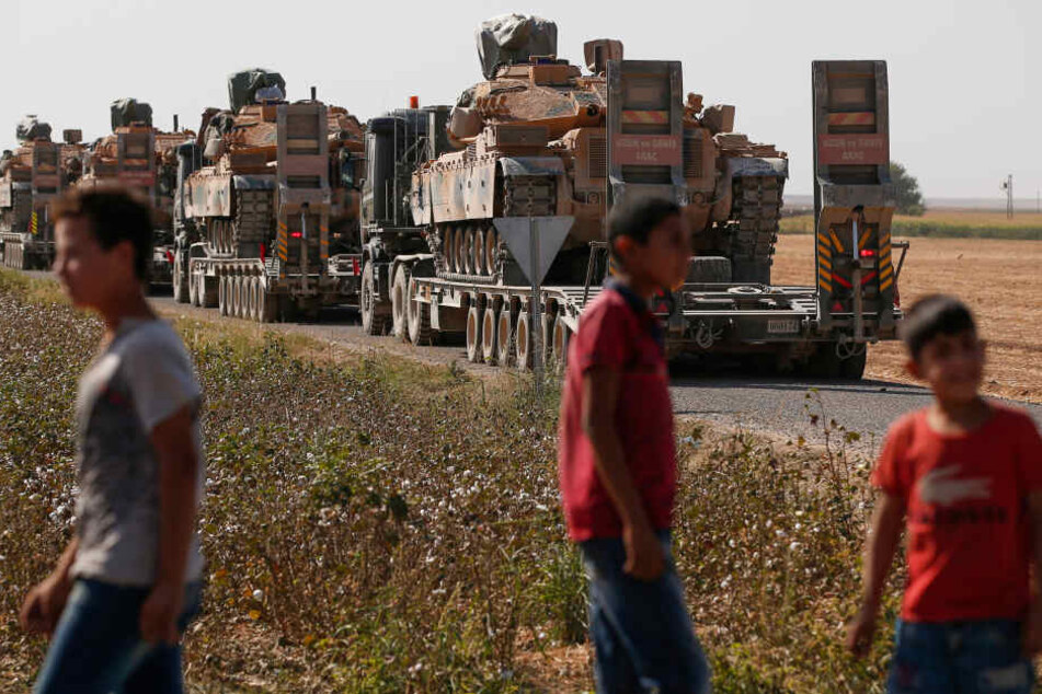 Anwohner stehen vor einem Lastwagen-Konvoi türkischer Streitkräfte, in dem Panzer transportiert werden. Die Türkei hatte am 09.10.2019 eine lang geplante Offensive gegen Kurdenmilizen begonnen, die auf syrischer Seite der Grenze ein großes Gebiet kontroll
