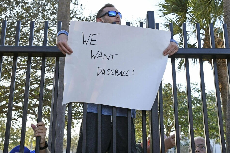 A baseball fan holds a signboard reading "We want baseball" while labor negotiations were being last week in Florida.
