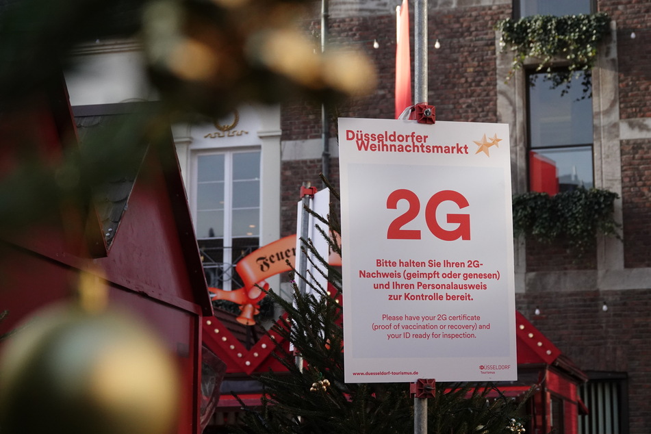 An einem Pfosten hängt ein Schild, das auf die 2G-Regelung auf dem Weihnachtsmarkt in Düsseldorf hinweist.