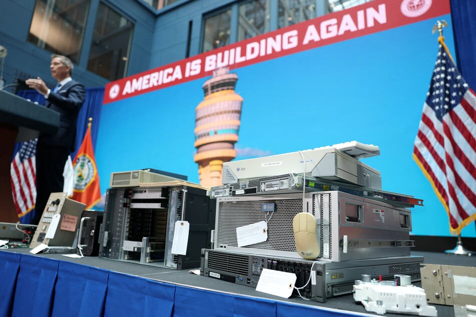 Transportation Secretary Sean Duffy is surrounded onstage by units representing outdated air traffic control equipment still in use.