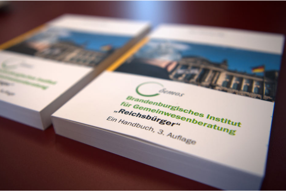 Handbücher zum Umgang mit den sogenannten Reichsbürgern liegen während einer Pressekonferenz im Brandenburger Innenministerium auf einem Tisch.