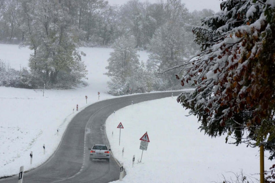 Ein Auto fährt durch die Schneelandschaft.