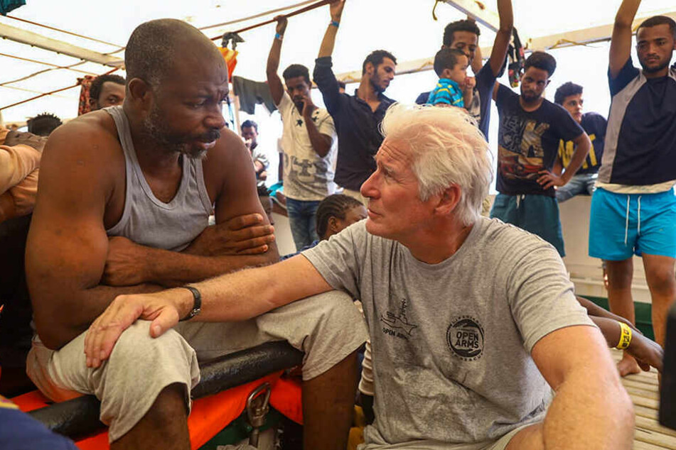 Richard Gere (re.) spricht mit einem Migranten an Bord des spanischen Rettungsschiffs "Open Arms" der Hilfsorganisation Proactiva Open Arms, das im Mittelmeer kreuzt.