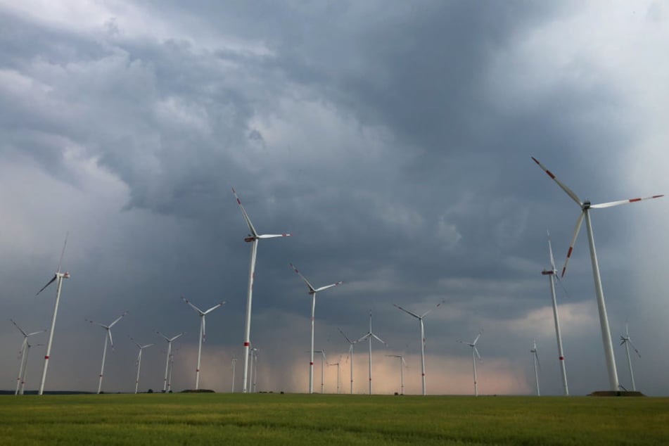 Dunkle Gewitterwolken ziehen über die Landschaft mit einem Windenergiepark in Brandenburg.