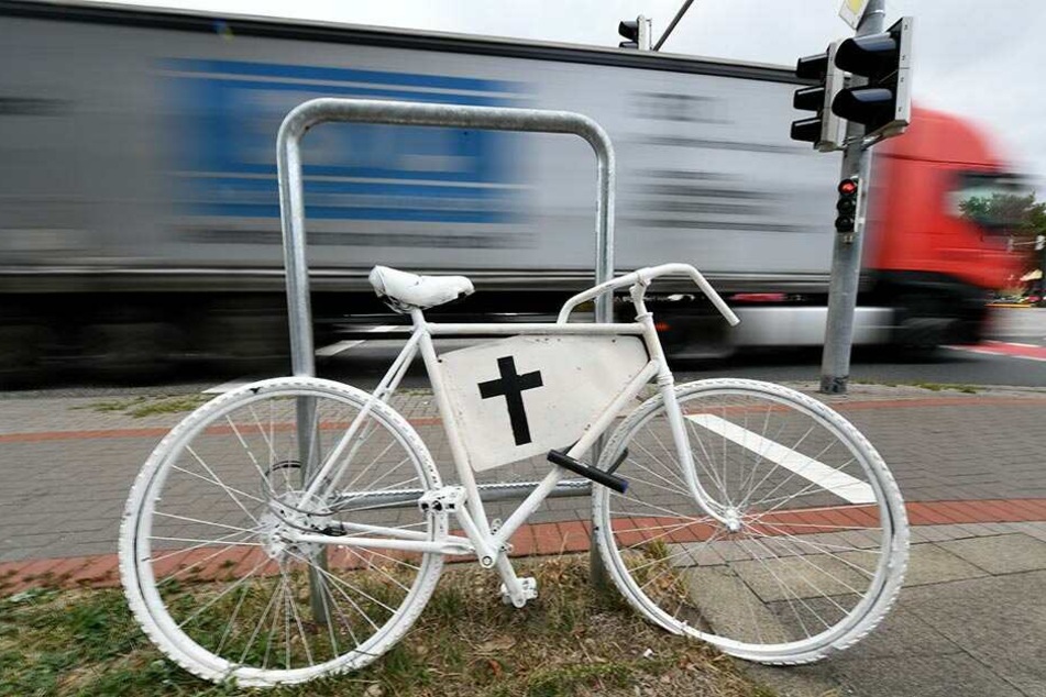 Ein weißes Fahrrad mit einem schwarzen Kreuz erinnert an einer Ampelkreuzung an einen Fahrradunfall mit tödlichen Ausgang.