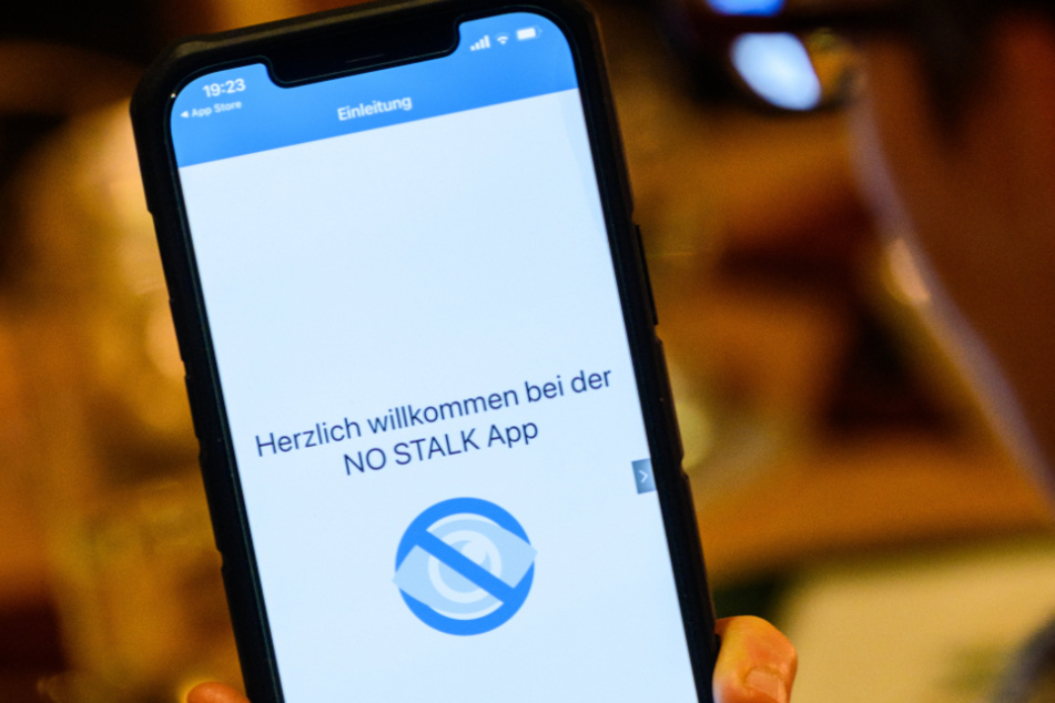 Eine Frau hält ein Smartphone mit geöffneter Stalking-App des Weißen Rings.