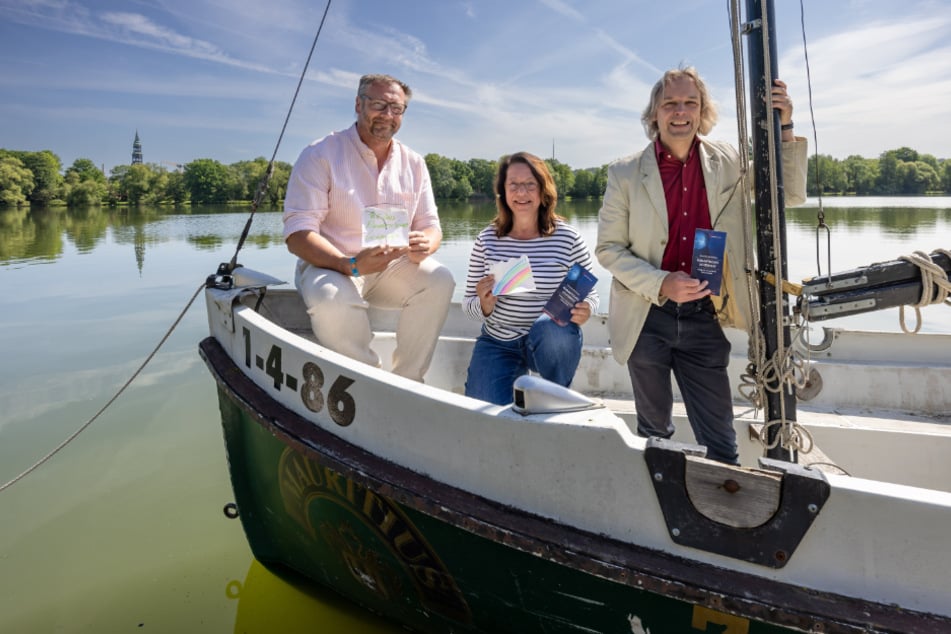 Die Veranstalter Thomas Kießig (47), Angela Hofmann (62) und Thomas Synofzik (v.l.) mit Papierlaternen in einem Segelboot.
