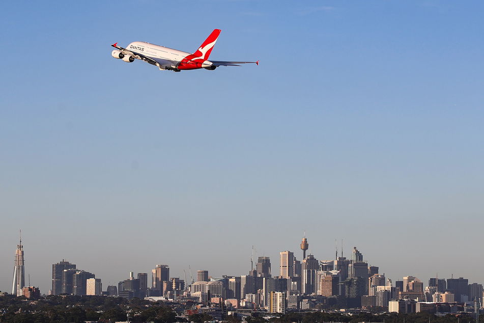 Eine Maschine der australischen Fluggesellschaft Qantas fliegt über der Stadt Sydney.