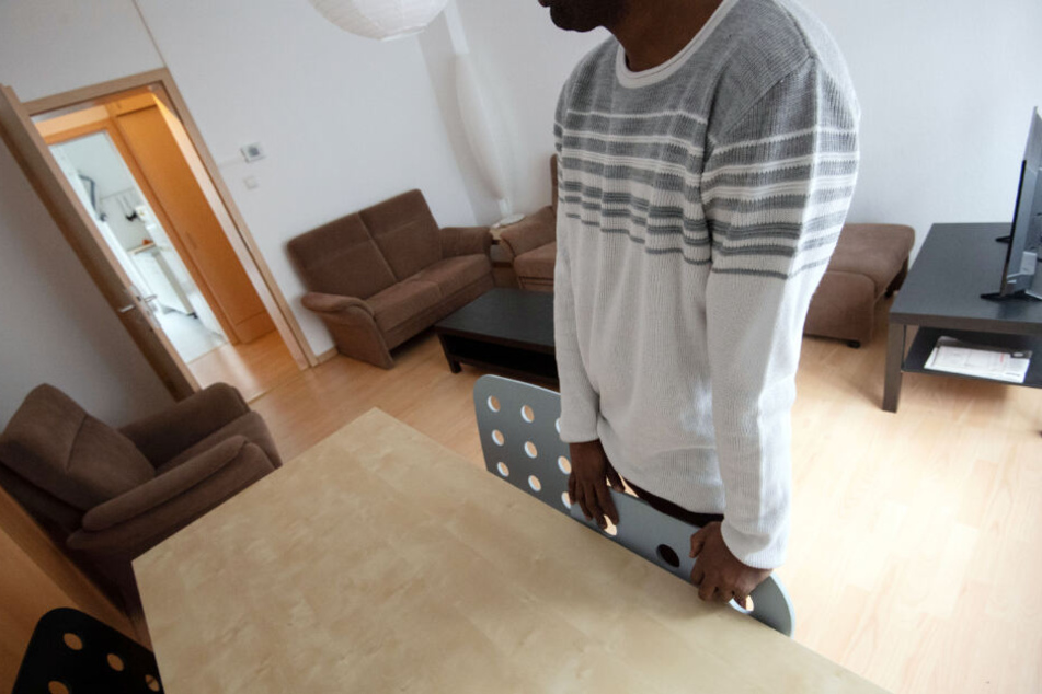 Ein Bewohner lehnt sich an einen Stuhl im Wohnzimmer der Männerschutzwohnung.