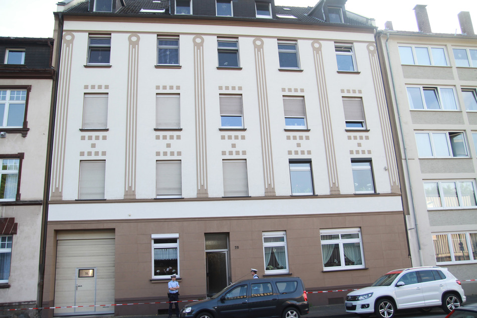 Polizisten stehen vor einem Mehrfamilienhaus. Nach dem Fund einer toten Frau in einem Keller in Hagen ermittelt eine Mordkommission wegen des Verdachts eines Gewaltverbrechens.