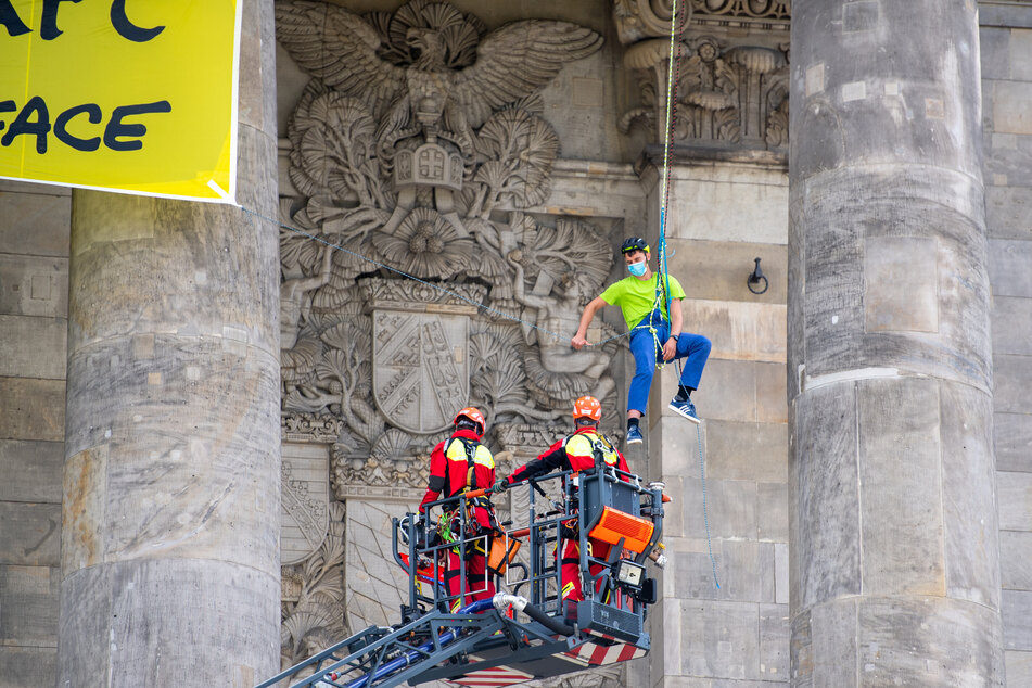 Ein Höhenrettungsteam der Feuerwehr wird im Kranwagen zu einem Greenpeace-Aktivisten am Reichstagsgebäude gefahren, der sich mit anderen Aktivisten mit einem Transparent am Gebäude abgeseilt hatte.