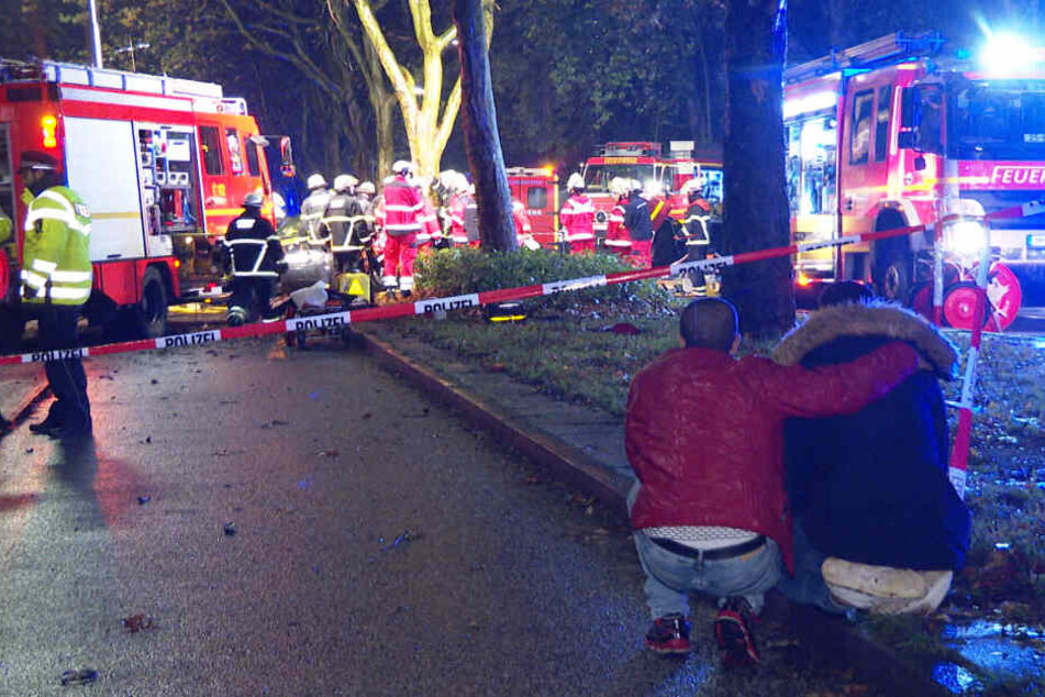 Zwei unverletzte Insassen aus einem der Unfallfahrzeuge beobachten die Rettungsaktion.
