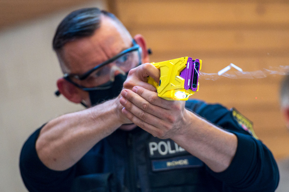 Ein Polizeibeamter demonstriert den Taser-Einsatz. (Archiv)