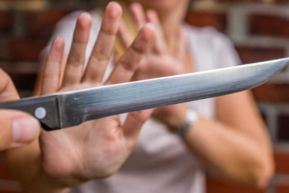 Eine Frau wird von einer Person mit einem Messer bedroht. (Symbolbild)