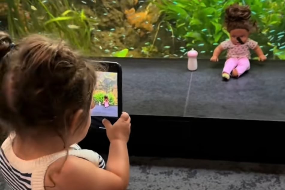 Die kleine Zahra macht in dem Video ein Foto ihrer Puppe.