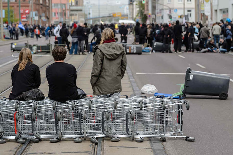 Teilnehmer einer Demonstration gegen einen geplanten Aufmarsch der rechten Szene haben am Straßenbarrikaden mit Mülltonnen und Einkaufswagen errichtet.