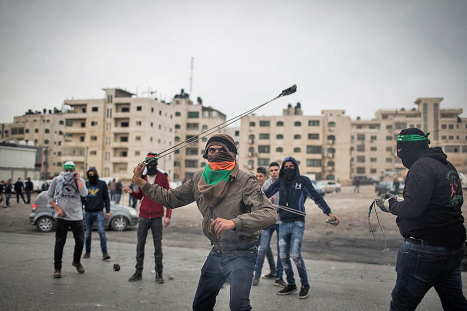 Palästinenser schleudern am 22.12.2017 in Ramallah im Westjordanland Steine auf israelische Soldaten.