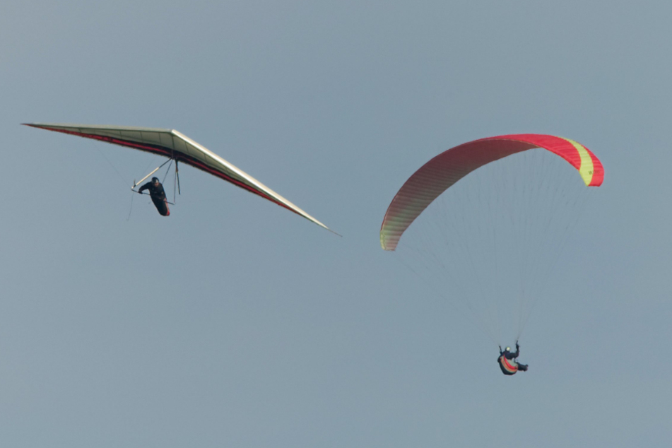 Ein Gleitschirm- und ein Drachenflieger kreisen in der Luft. (Symbolbild)