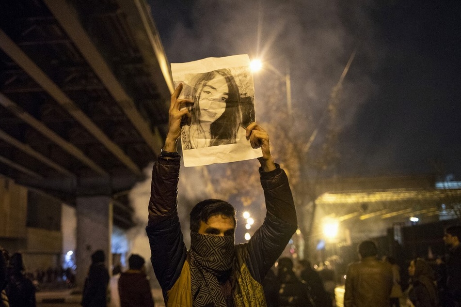 An Iranian man holds a picture of a victim of the Ukrainian Boeing 737-800 plane crash during a demonstration in Tehran.