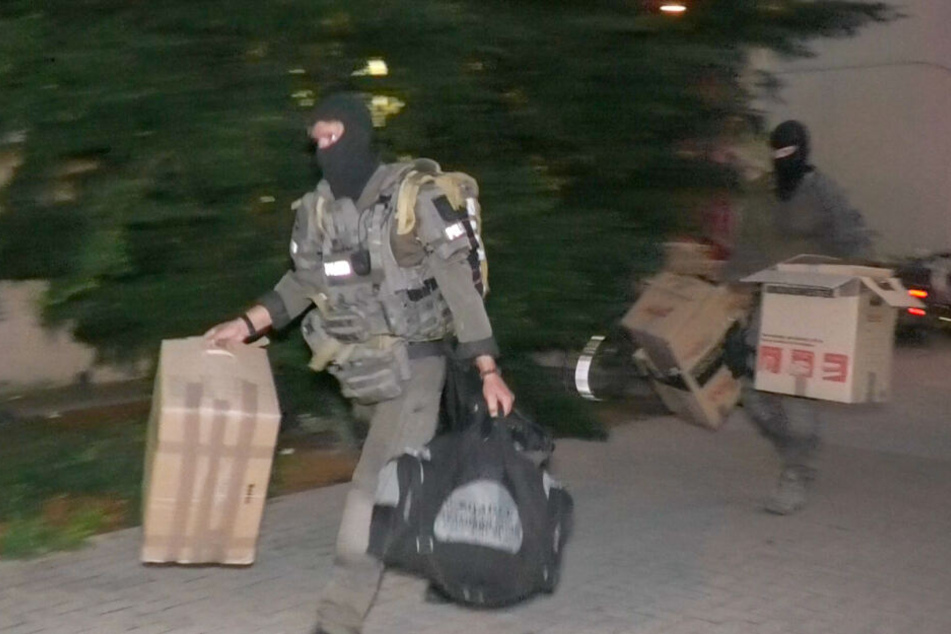 Kistenweise schleppten die Beamten Beweismaterial nach draußen.