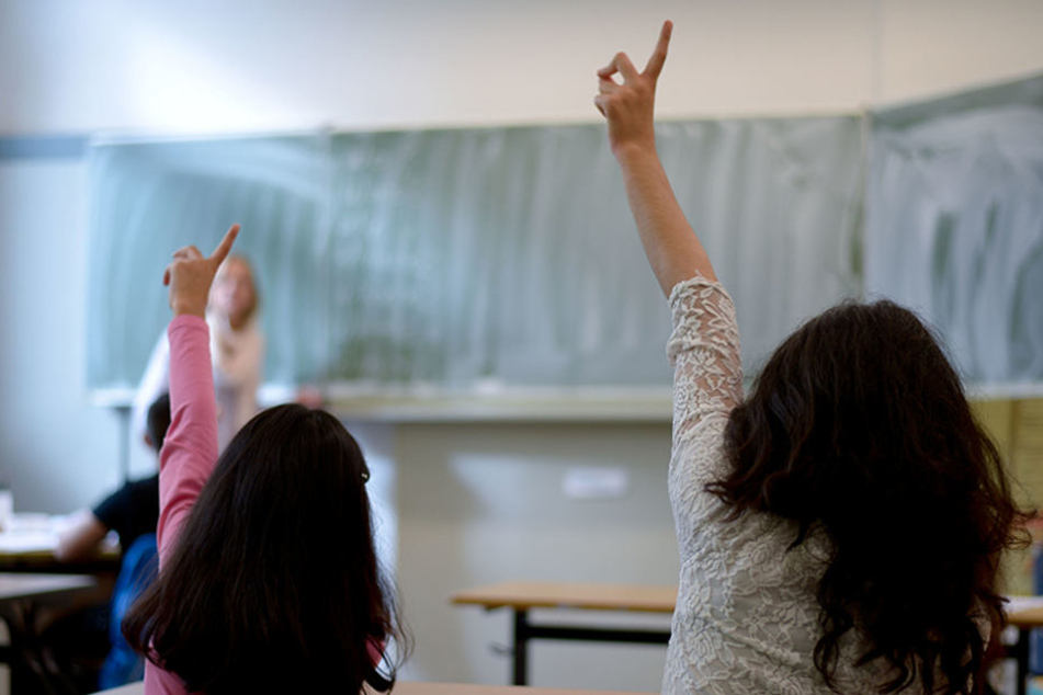 Flüchtlingsmädchen melden sich während des Unterrichts in einer Sprachlernklasse.