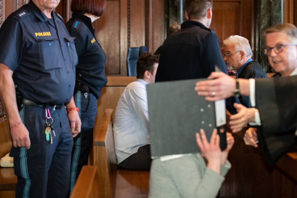 Ein 26-Jähriger (M) und dessen Ehefrau (v) sitzen auf der Anklagebank im Sitzungssaal im Landgericht Nürnberg-Fürth. Das wegen zweifachen Mordes angeklagte Paar soll zunächst versucht haben, die Mutter des Mannes zu vergiften.