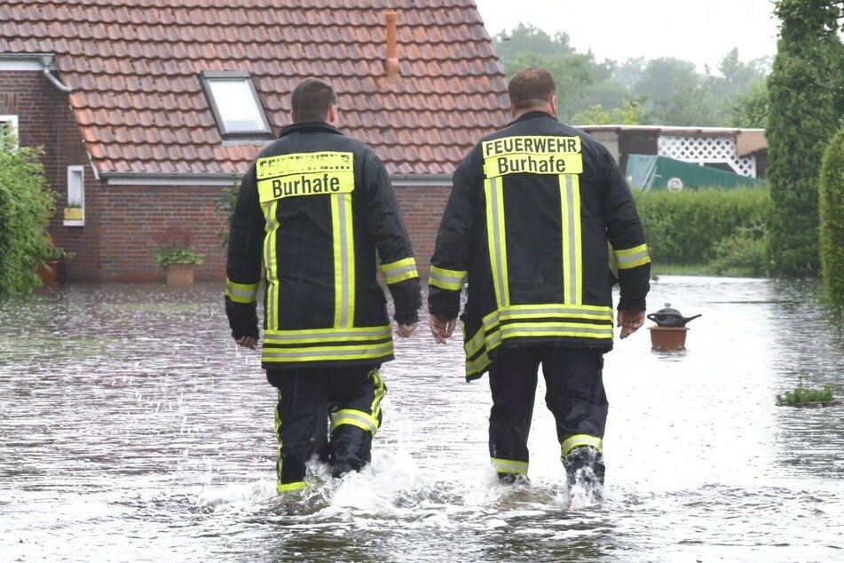 Feuerwehrleute gehen durch eine der überfluteten Straßen.