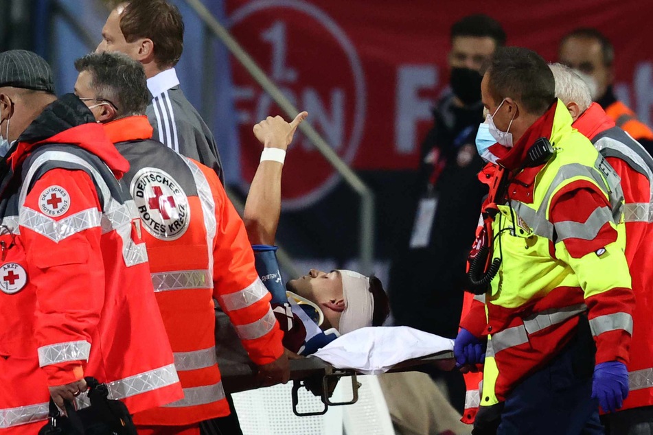 Der Nürnberger Tom Krauß wird verletzt aus dem Stadion getragen, zeigt aber mit dem Daumen nach oben.